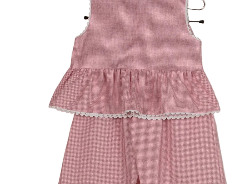 Pink checkered dress with ruffled layers and lace trim on a beige background