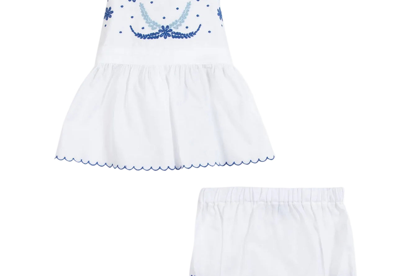 White baby dress with blue floral embroidery on a white background